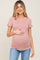woman wearing a dusty rose fitted maternity top and holding her baby bump, paired with light blue jeans