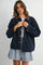 woman wearing a navy corduroy jacket with a brown collar, paired with a plaid mini skirt and a white top