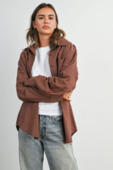 woman wearing a brown checkered oversized button-up shirt with a white t-shirt and light blue jeans