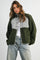 woman wearing an olive green and plaid check oversized button-up fleece jacket with dropped shoulders and a relaxed fit