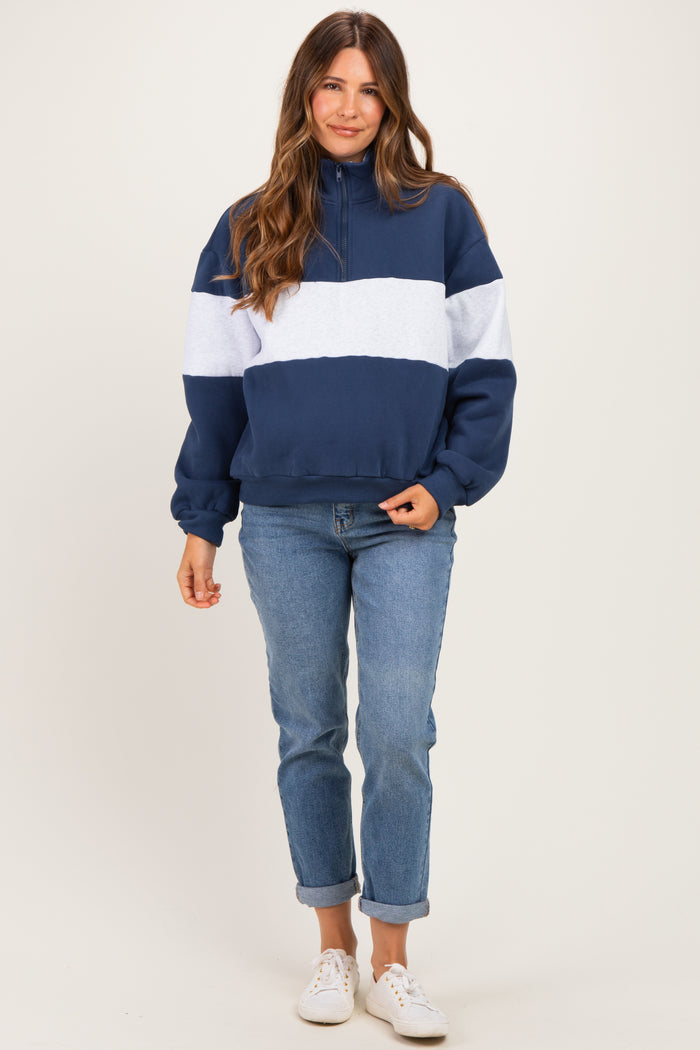 woman wearing a navy blue and light gray color block maternity hoodie and relaxed fit jeans