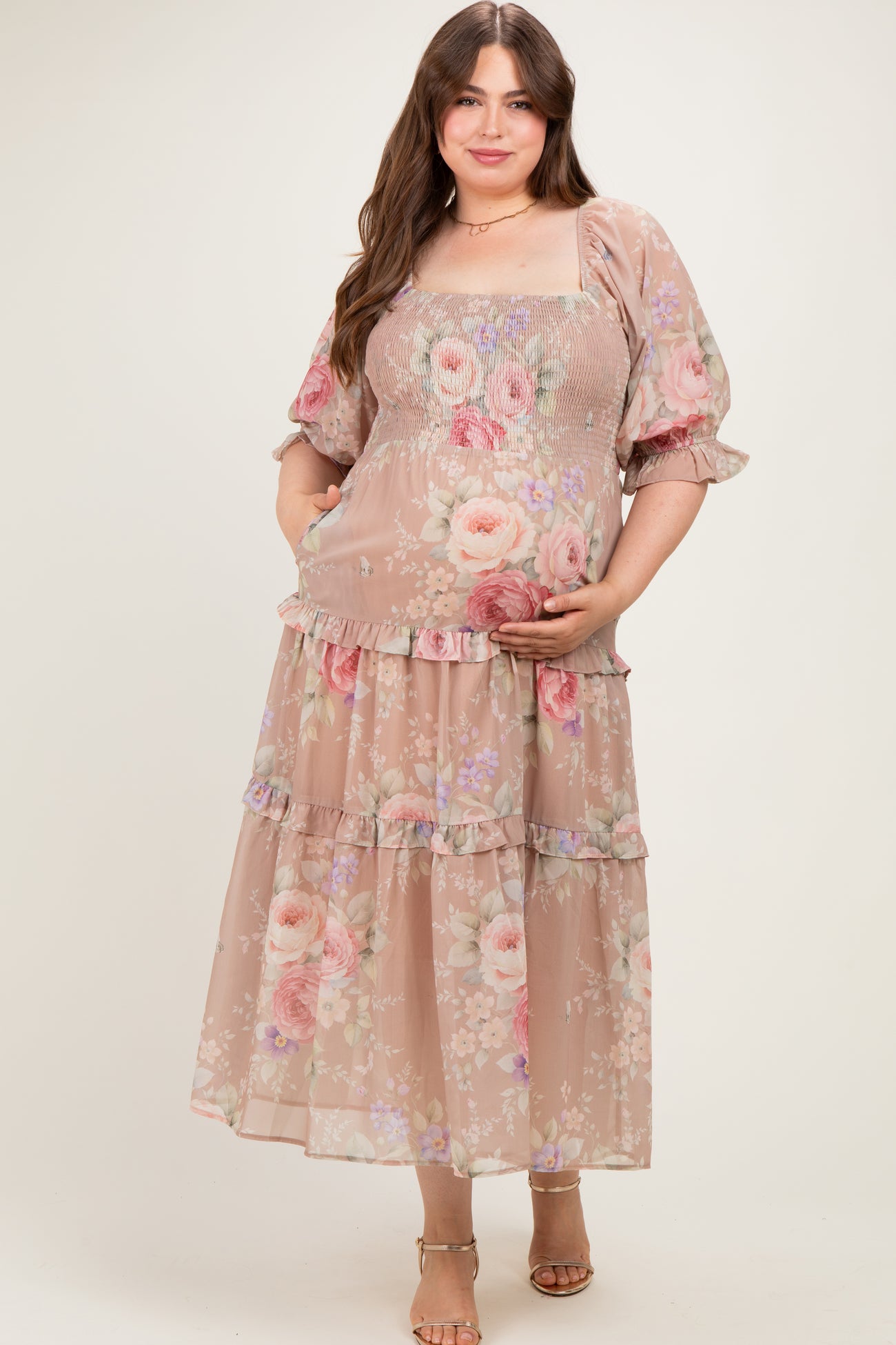 woman wearing a floral maternity plus dress with smocked bodice and tiered skirt, holding her baby bump