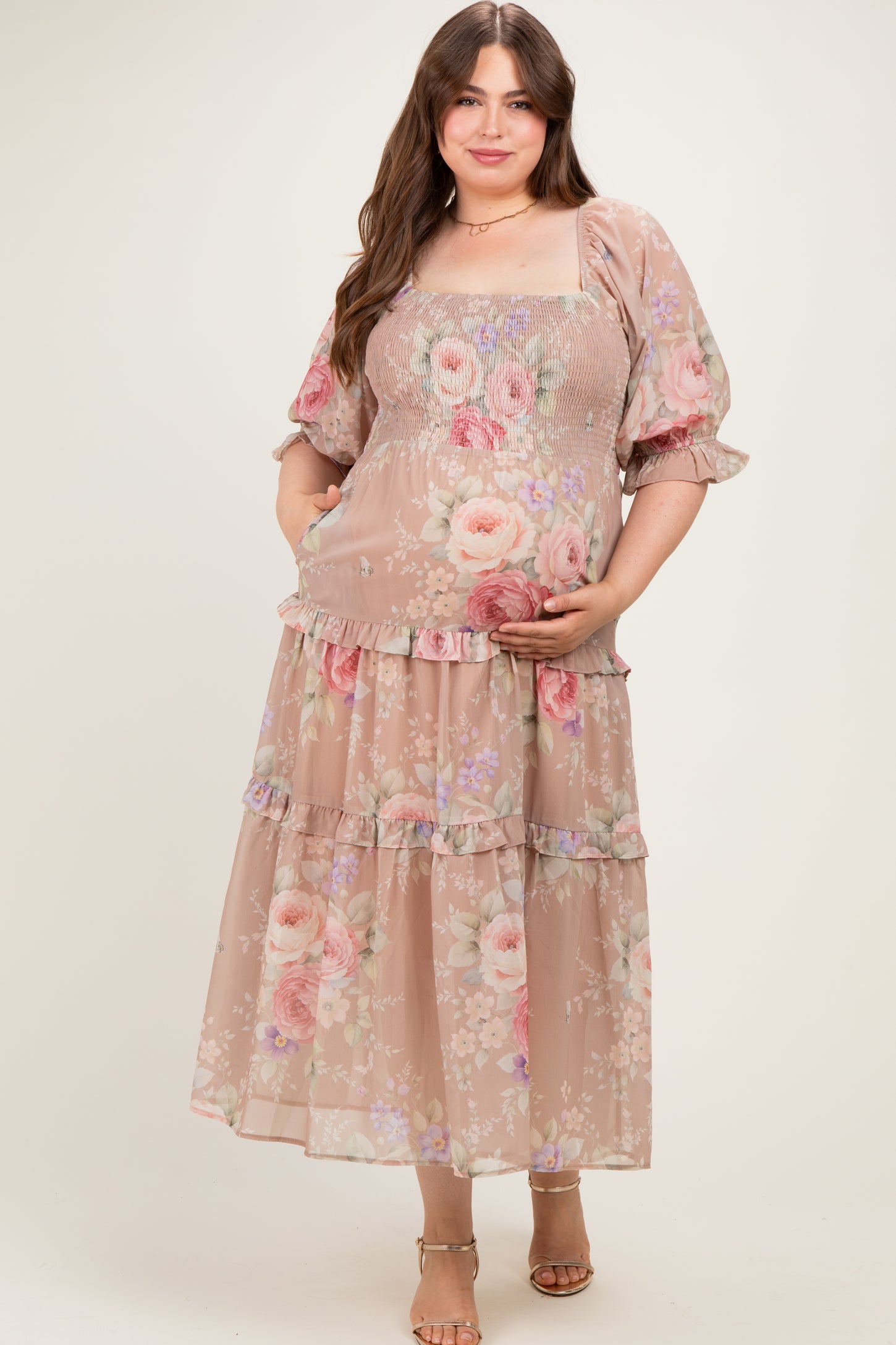 woman wearing a floral maternity plus dress with smocked bodice and tiered skirt, holding her baby bump