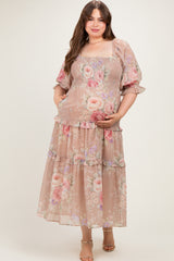 woman wearing a floral maternity plus dress with smocked bodice and tiered skirt, holding her baby bump