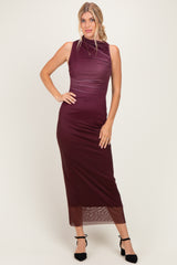 woman wearing a burgundy sleeveless midi dress with a high neckline and sheer bottom hem