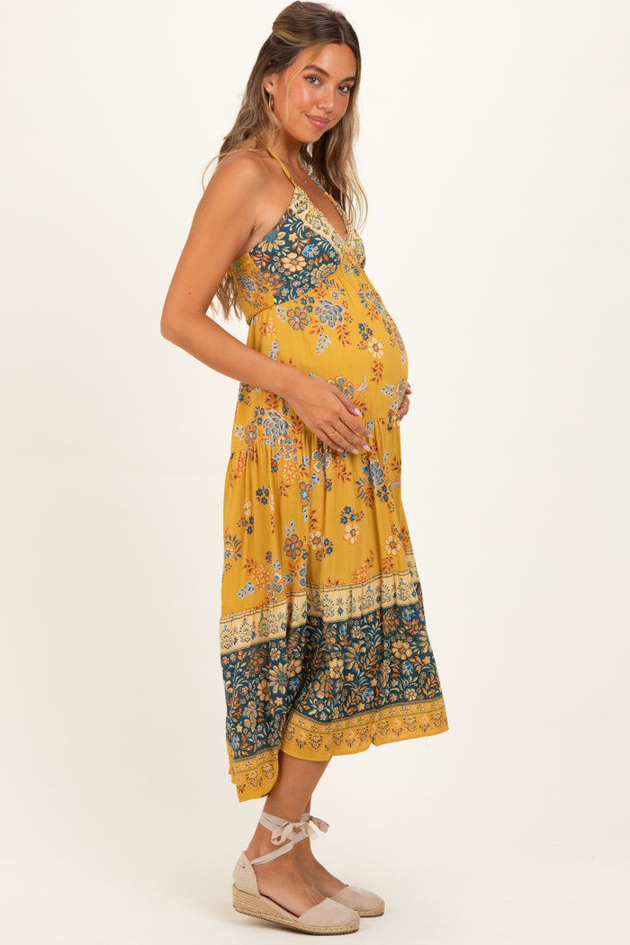 woman wearing a yellow floral maternity maxi dress and holding her baby bump