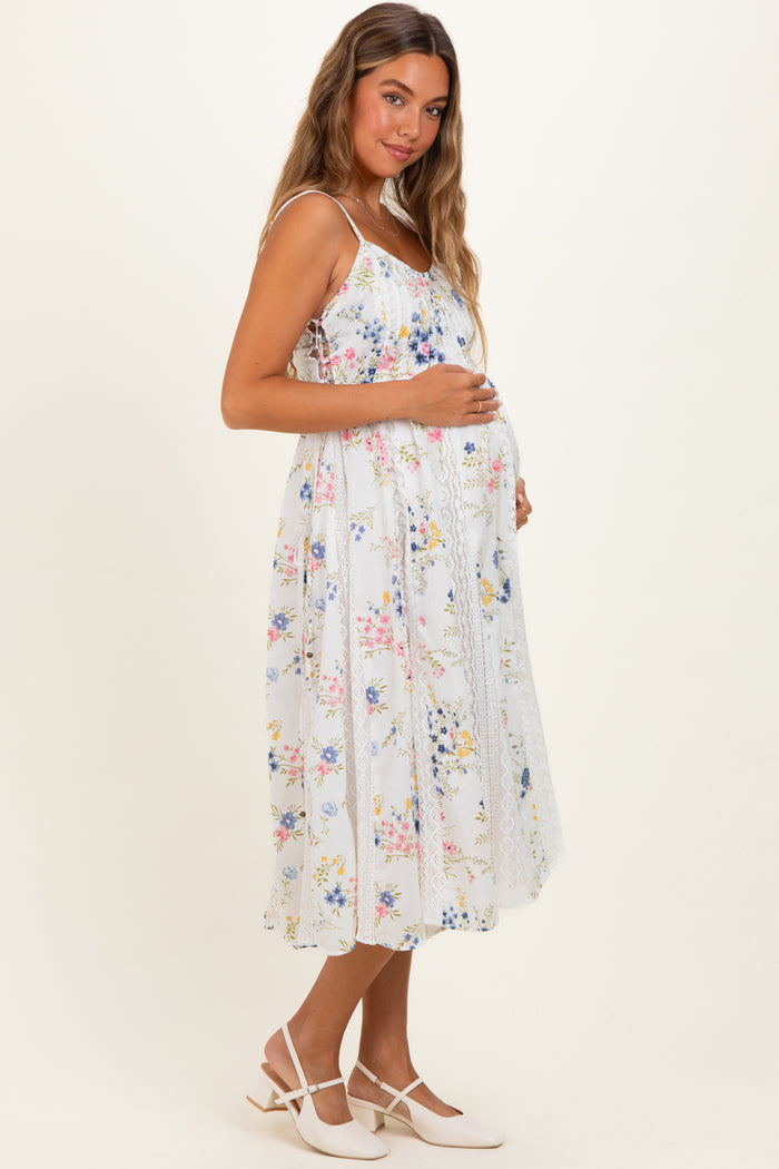 woman wearing a white floral maternity dress with a flowy silhouette and a visible baby bump