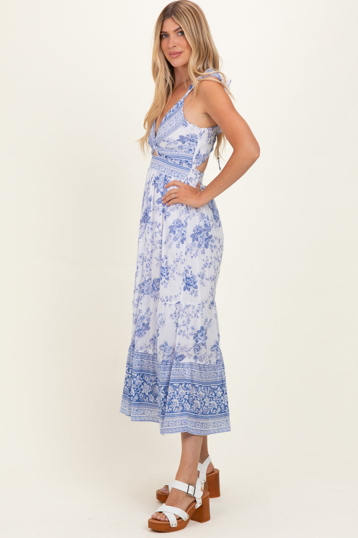 woman wearing a blue and white floral maxi dress with a fitted bodice and flowy skirt, standing sideways with heels