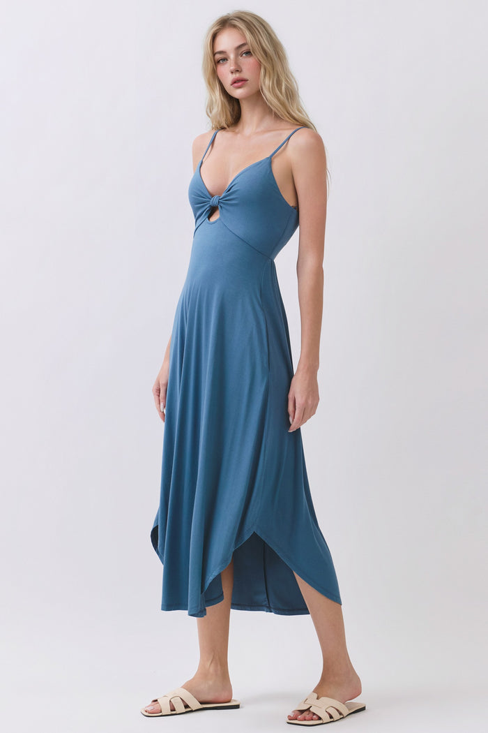 woman wearing a blue spaghetti strap midi dress with a front knot detail and an asymmetrical hemline
