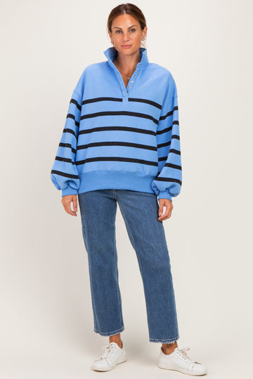 woman wearing a light blue striped sweatshirt with a collar and button detail, paired with blue jeans