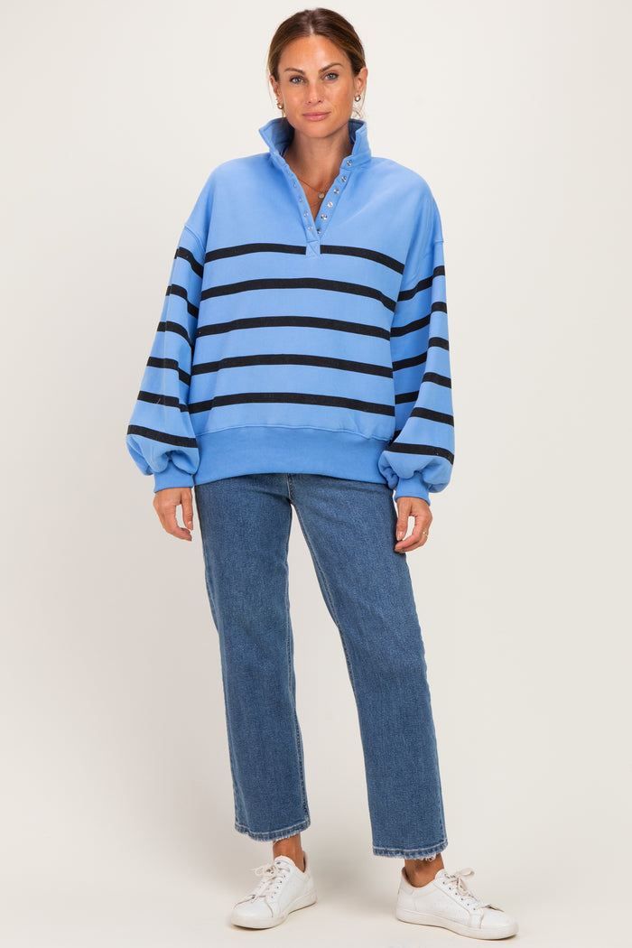 woman wearing a light blue striped sweatshirt with a collar and button detail, paired with blue jeans