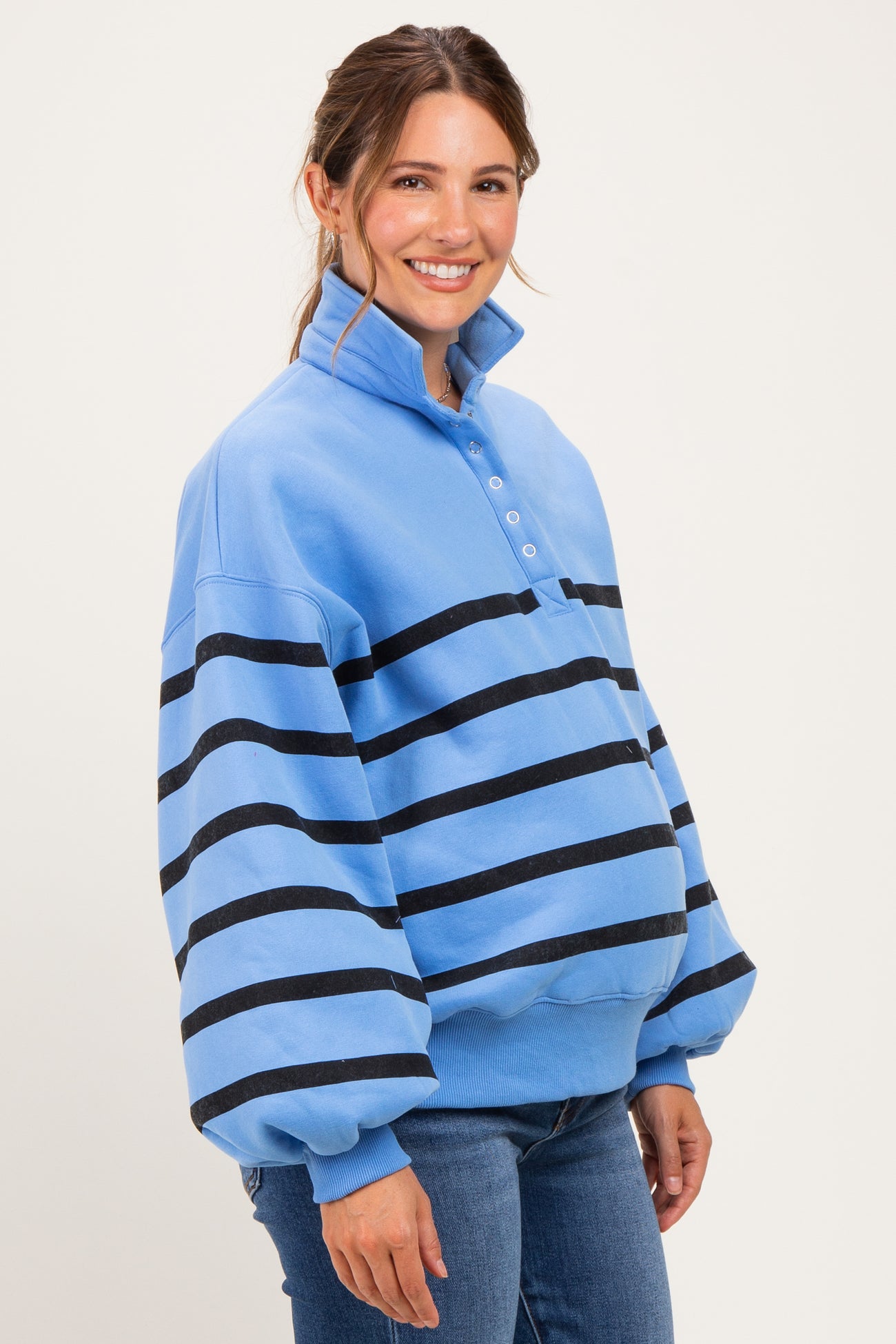 woman wearing a light blue maternity pullover with black stripes and a collar, showcasing her baby bump