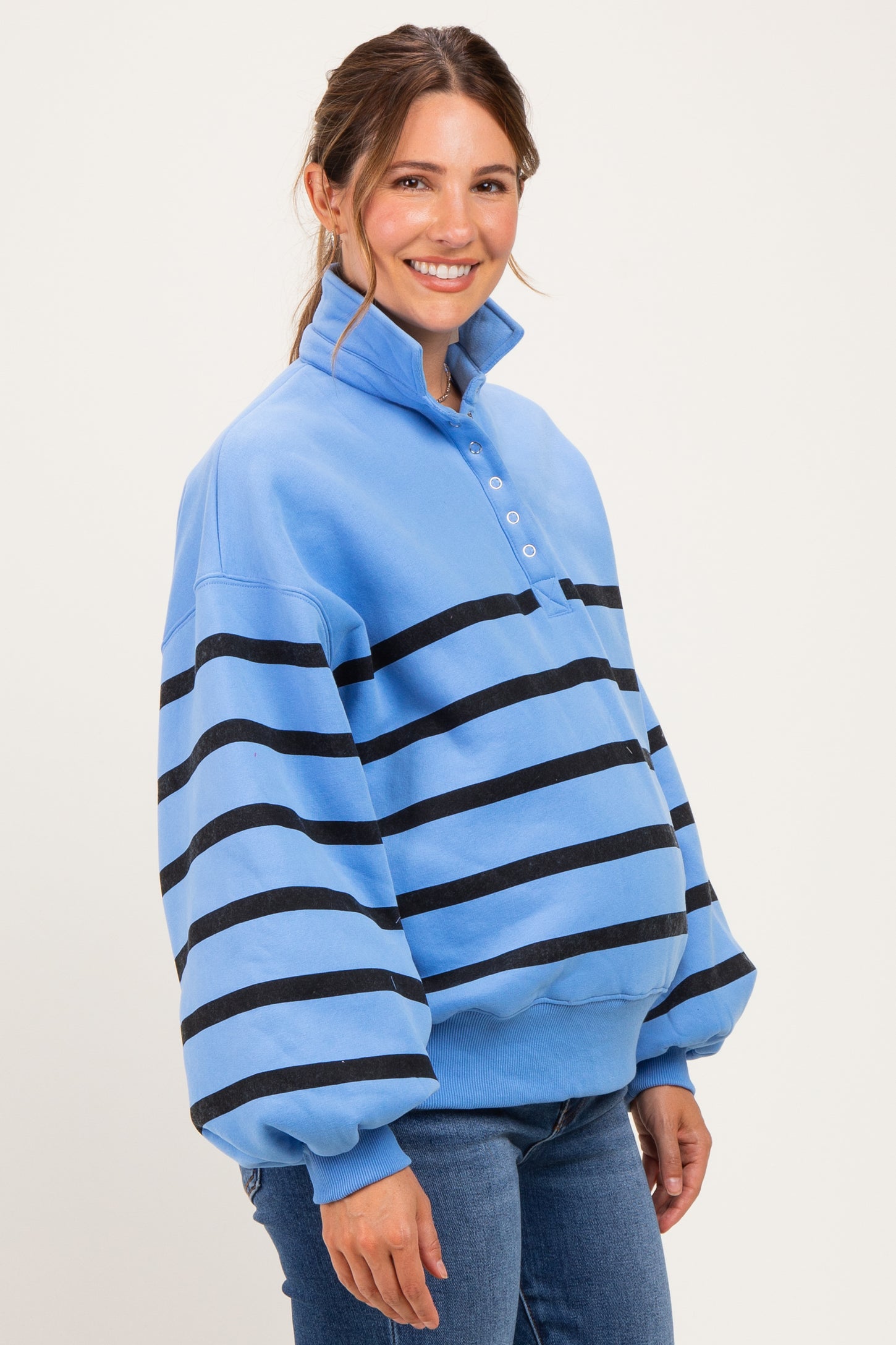woman wearing a light blue maternity pullover with black stripes and a collar, showcasing her baby bump