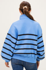 woman wearing a blue maternity sweatshirt with black stripes and oversized sleeves, styled with jeans