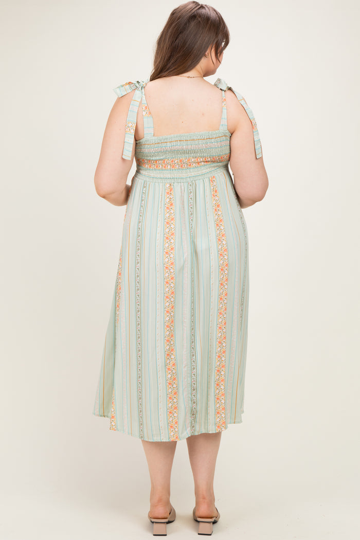 woman wearing a green and orange striped maternity dress with smocked bodice and tie straps, showing a baby bump from the back