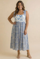 woman wearing a blue and white floral midi dress with tie straps and a relaxed fit