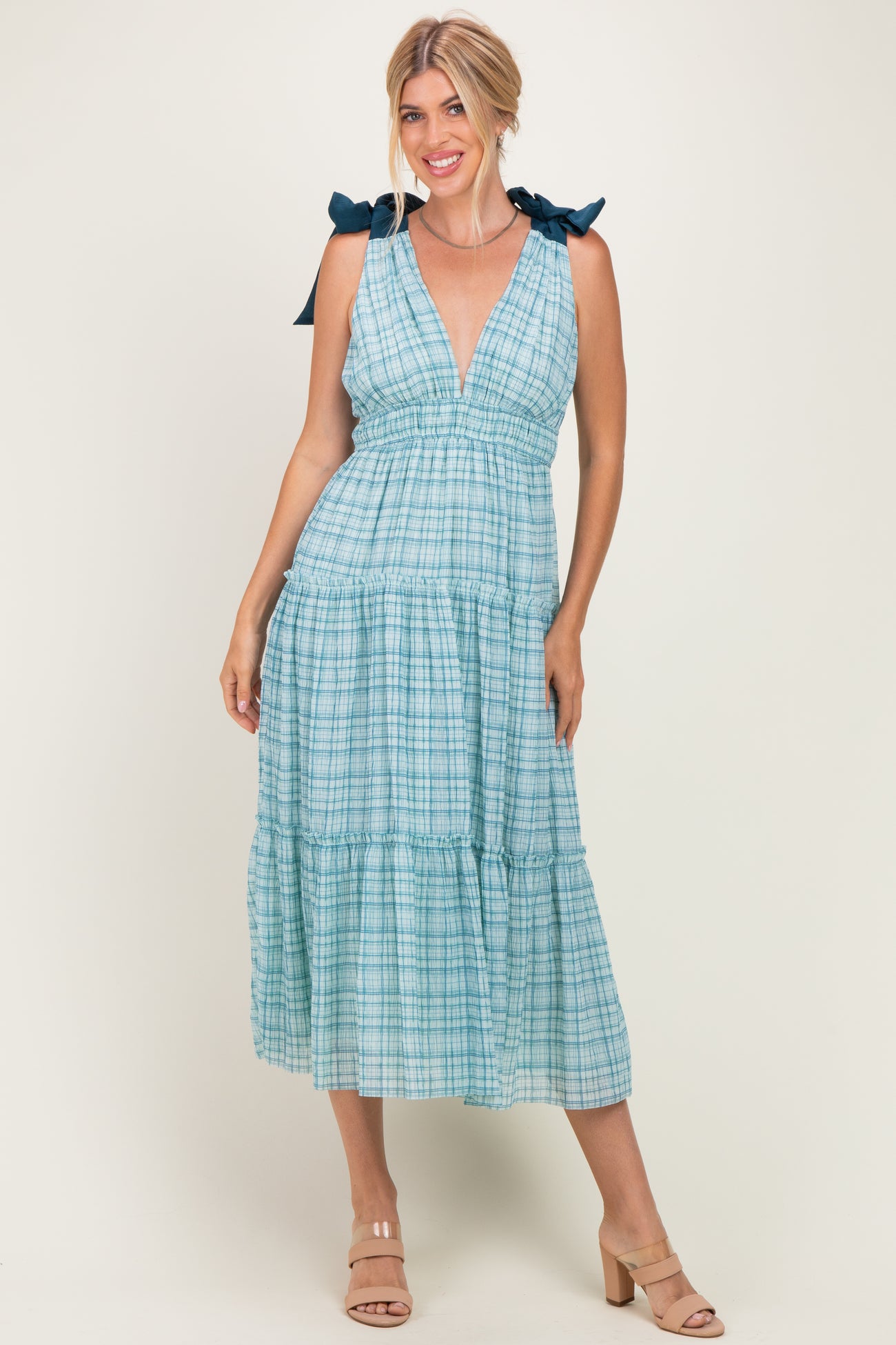 woman wearing a blue plaid midi dress with tie straps and a tiered skirt