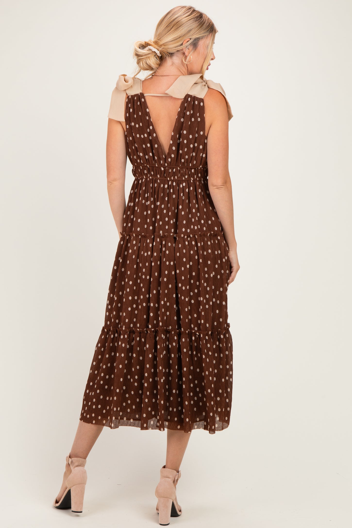 woman wearing a brown polka dot maxi dress with a v-back and ruffled skirt, shown from the back