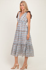 woman wearing a blue and brown checkered midi dress with ruffled sleeves and a tiered skirt