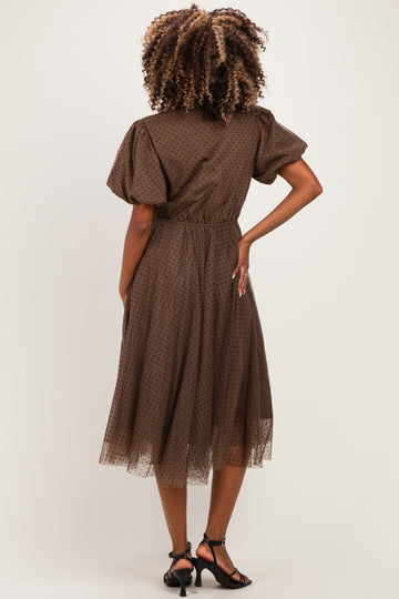 woman wearing a brown polka dot maternity dress with short puff sleeves and a flowy midi skirt from the back