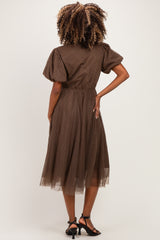 woman wearing a brown polka dot maternity dress with short puff sleeves and a flowy midi skirt from the back