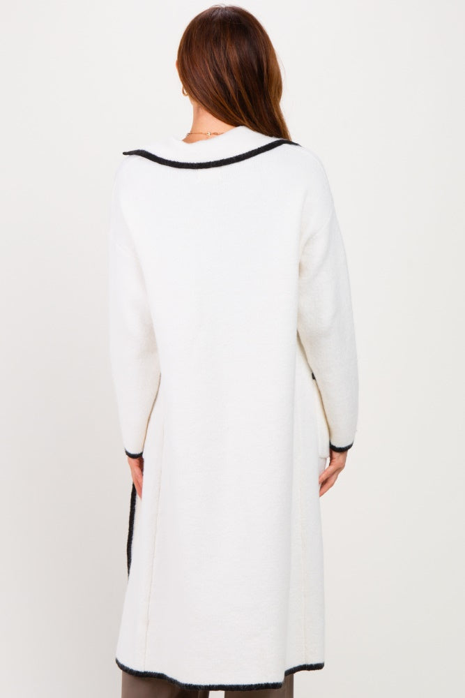 woman wearing an ivory long cardigan with black trim, displayed from the back