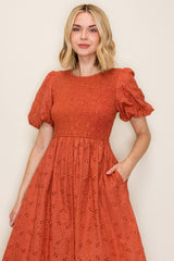 woman wearing an orange puff sleeve dress with a smocked bodice and pockets