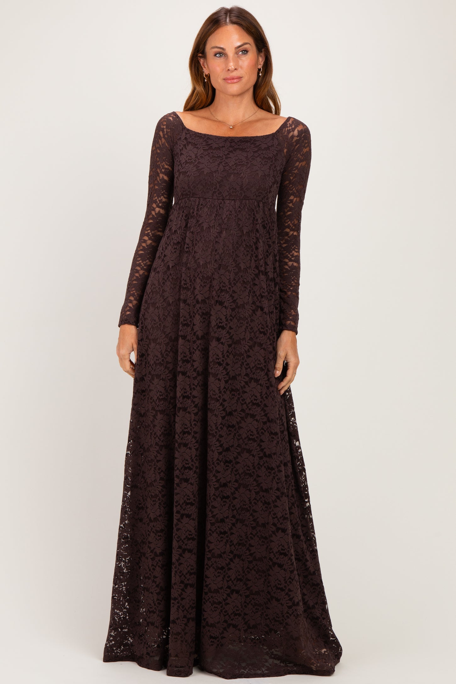 woman wearing a long sleeve dark brown lace maxi dress with a fitted bodice and flowing skirt
