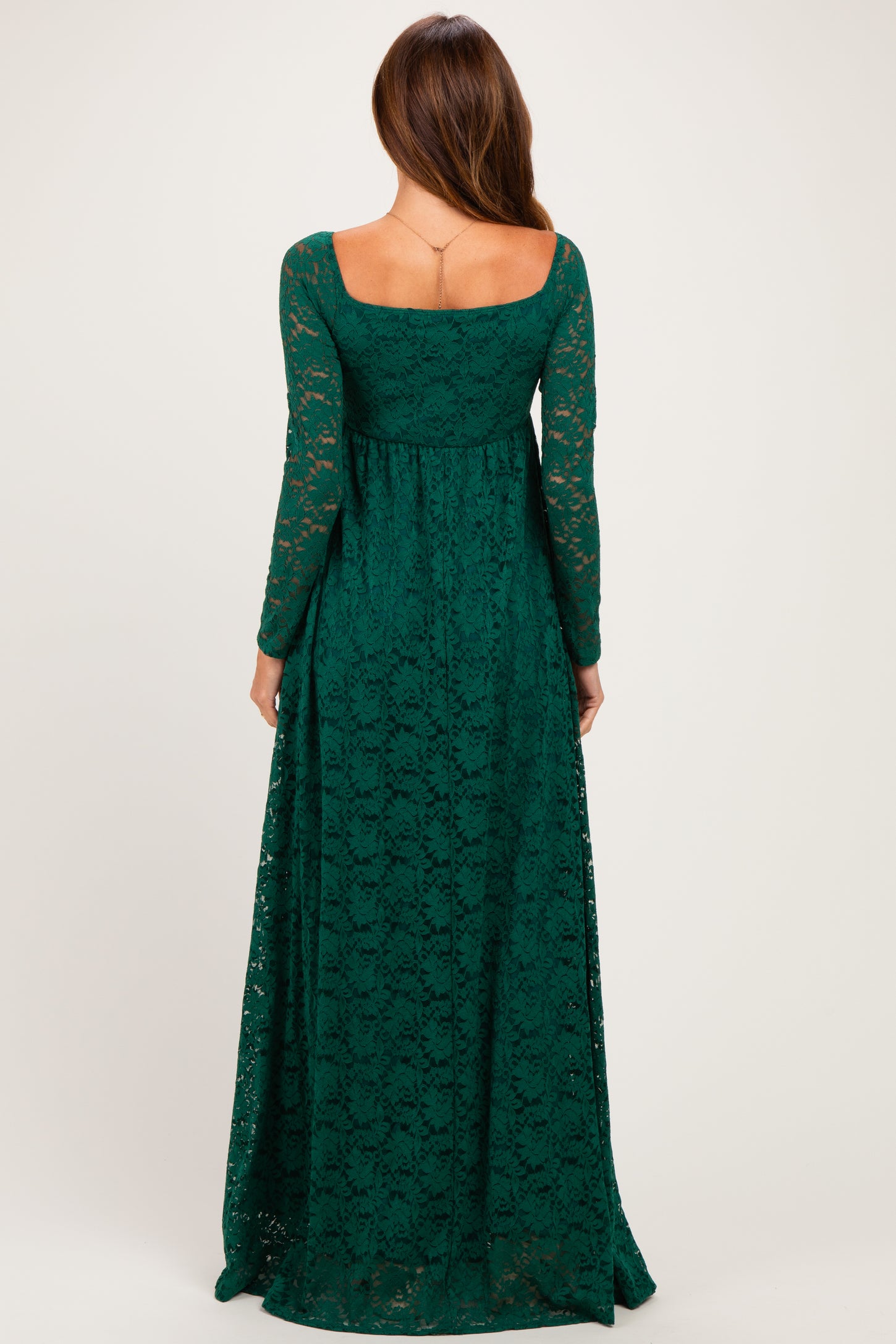woman wearing a long sleeve dark green lace maxi dress with a fitted bodice and flared skirt, shown from the back