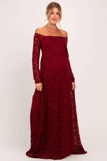 woman wearing a burgundy off-the-shoulder lace maternity dress with long sleeves and a visible baby bump
