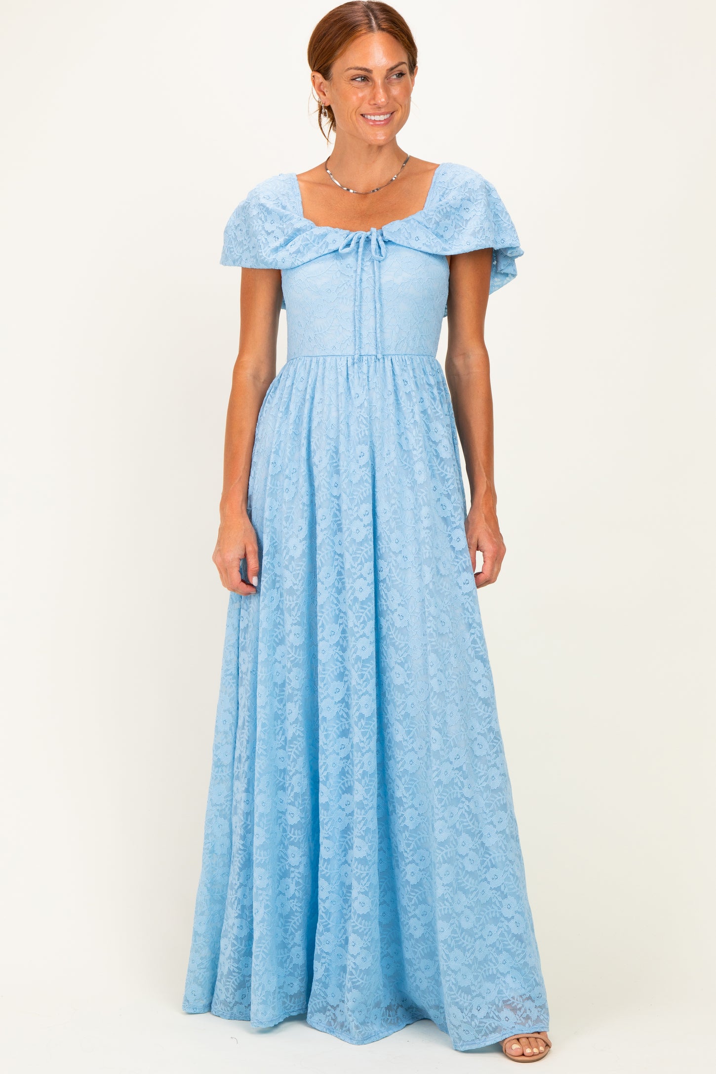 woman wearing a light blue maxi dress with short flutter sleeves and a tied neckline