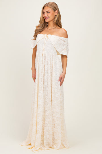 woman wearing a cream off-the-shoulder lace maxi dress with a drawstring waist and flowing skirt