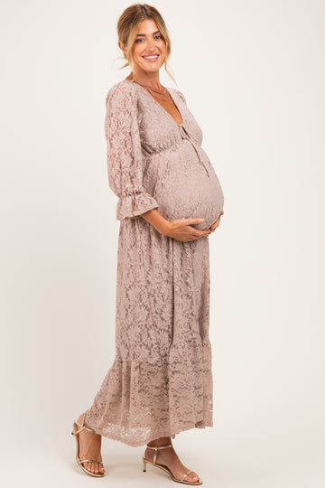 woman wearing a taupe lace maternity maxi dress and holding her baby bump