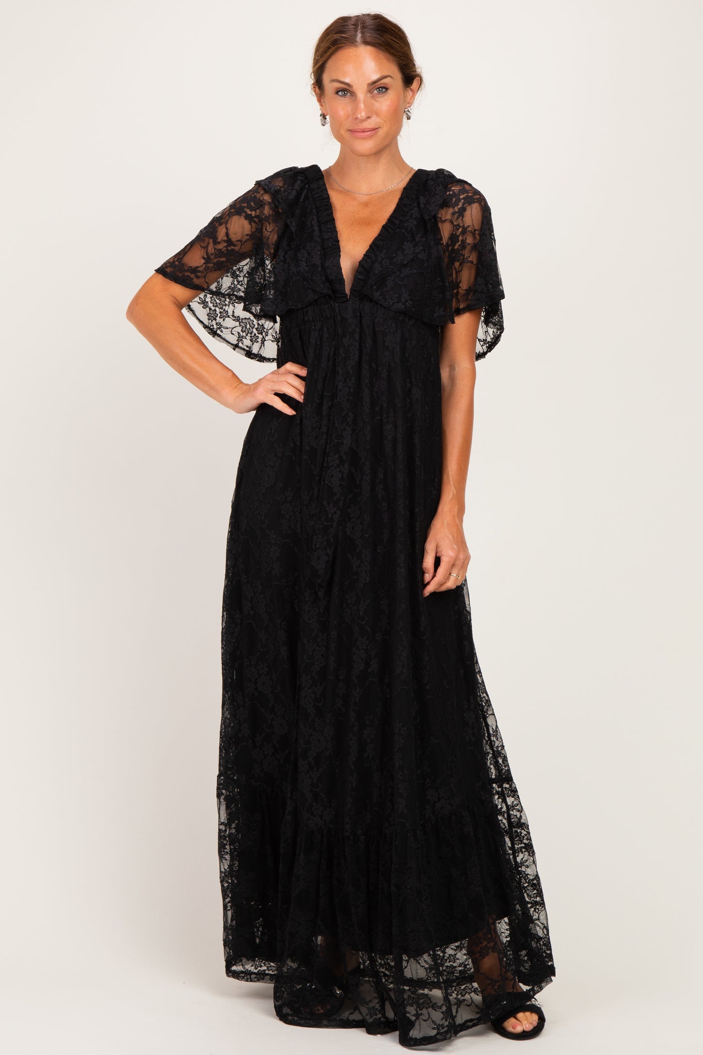 woman wearing a black lace maxi dress with flutter sleeves and a deep v-neckline