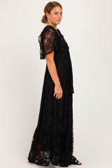 woman wearing a black lace maxi dress with short flutter sleeves and tiered skirt details