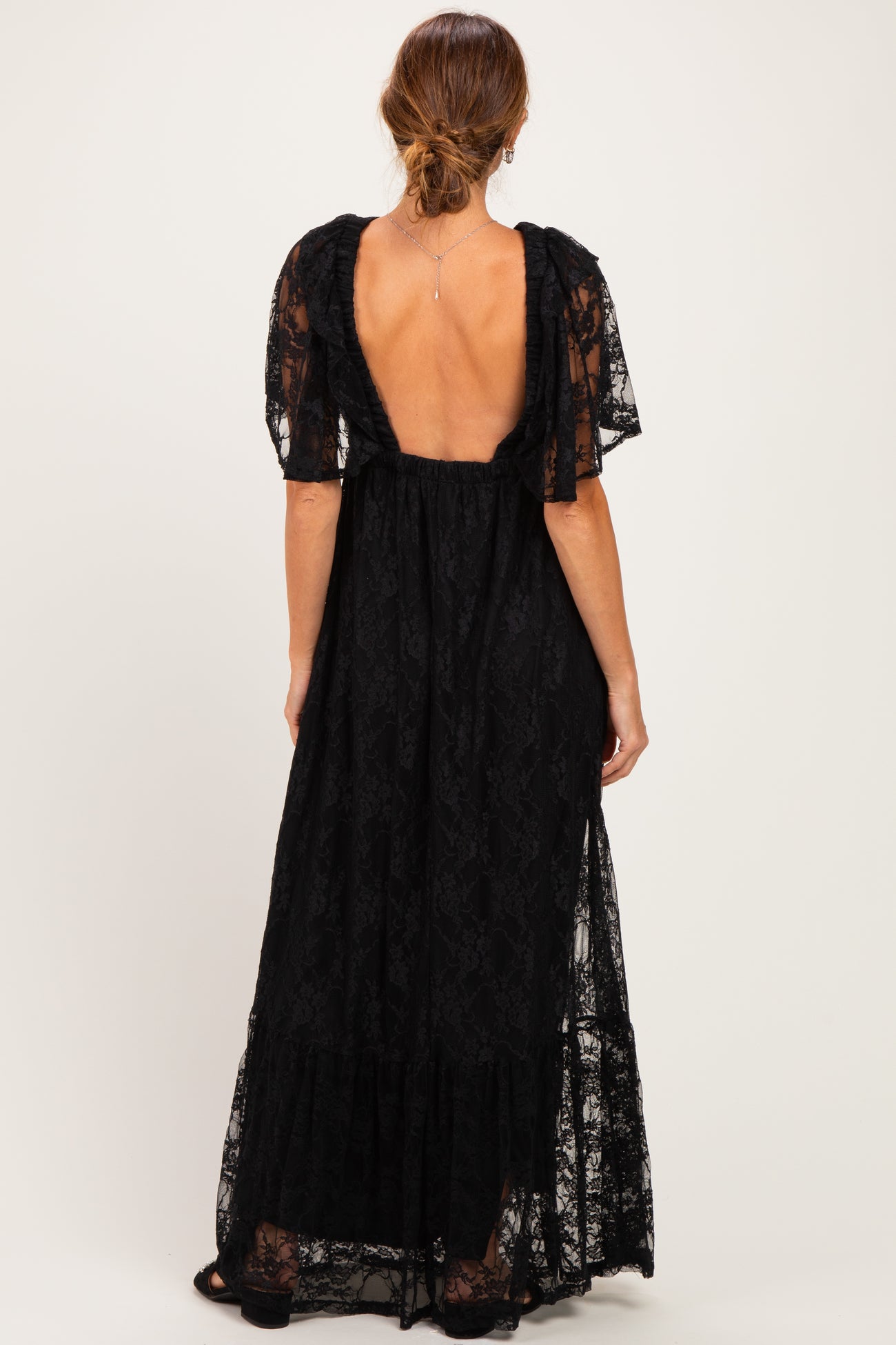 woman wearing a black lace maxi dress with short flutter sleeves and a deep back cutout