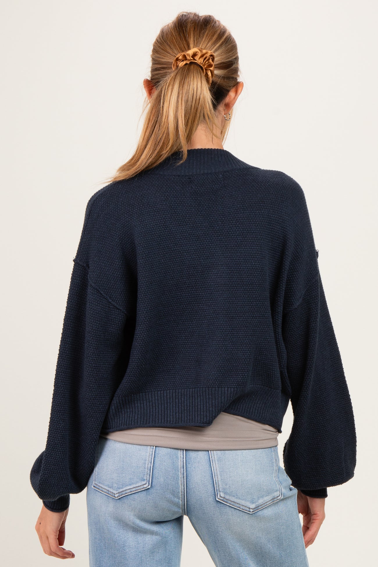 woman wearing a navy blue maternity sweater with a loose fit and balloon sleeves, seen from the back
