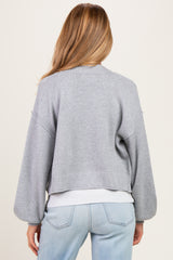 woman wearing a light gray cropped maternity cardigan with balloon sleeves, from the back