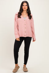 woman wearing a pink oversized cardigan with buttons, paired with a gray top and black leggings