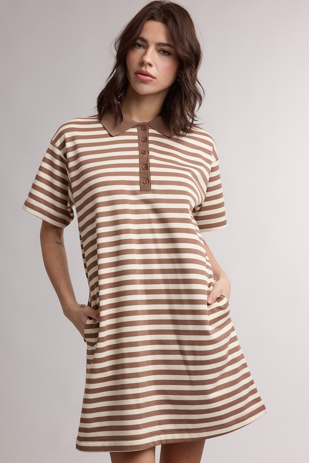 woman wearing a brown and cream striped polo dress with short sleeves and pockets