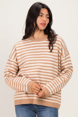woman wearing a beige and white striped oversized sweater with long sleeves and a relaxed fit