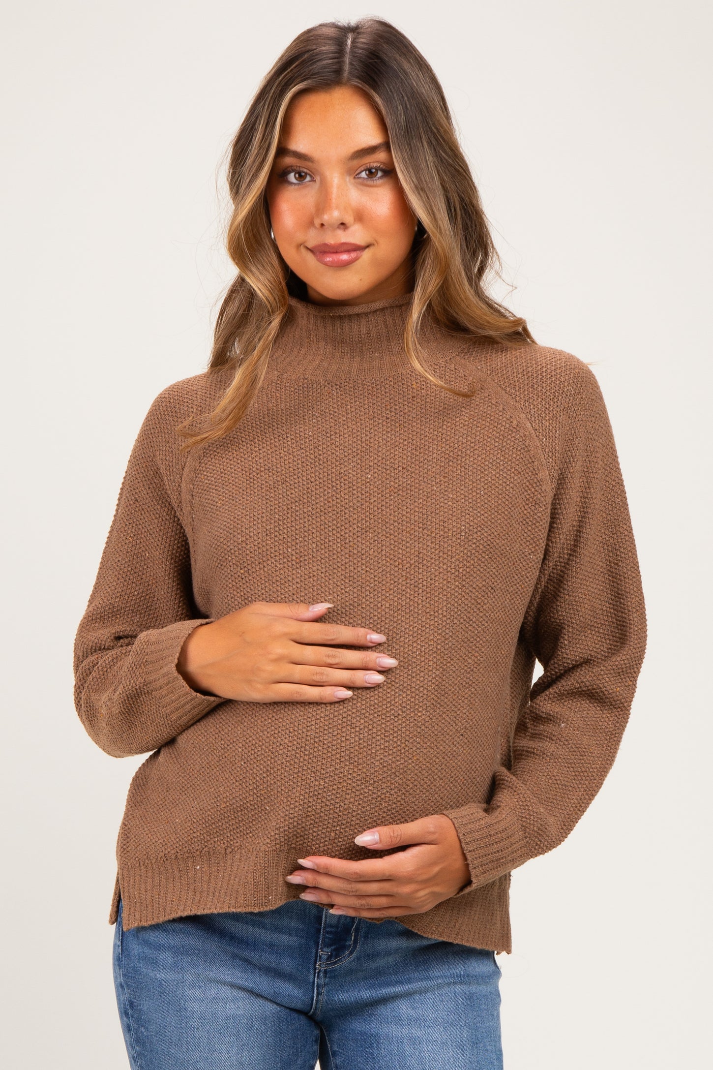 woman wearing a brown ribbed maternity sweater and holding her baby bump