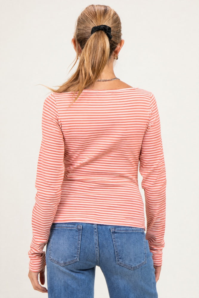 woman wearing a pink and white striped maternity long sleeve top, seen from the back with a ponytail hairstyle