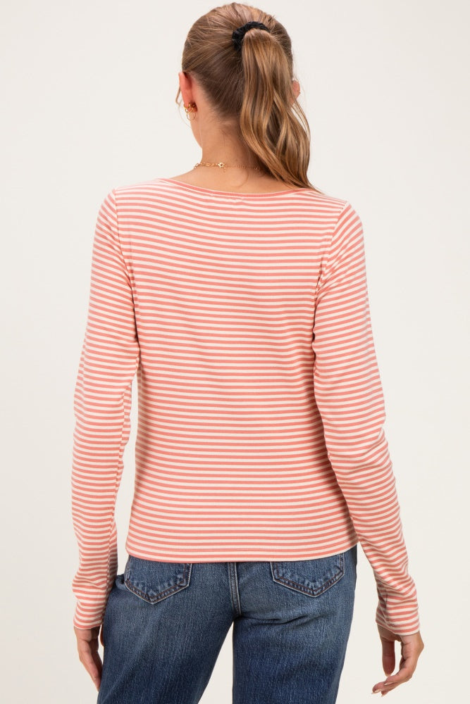 woman wearing a peach and white striped long sleeve maternity top, viewed from the back with dark jeans