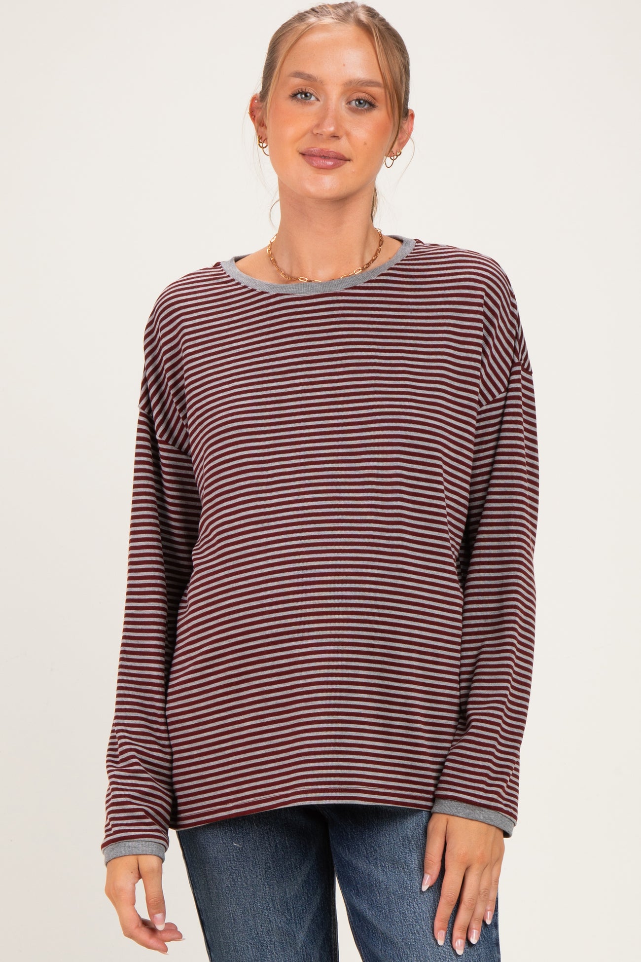 woman wearing a maroon and cream striped maternity top with long sleeves and a relaxed fit