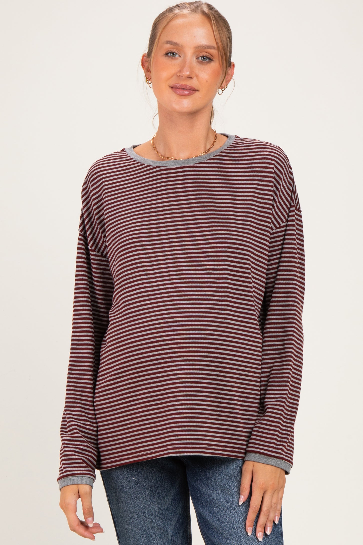 woman wearing a maroon and cream striped maternity top with long sleeves and a relaxed fit