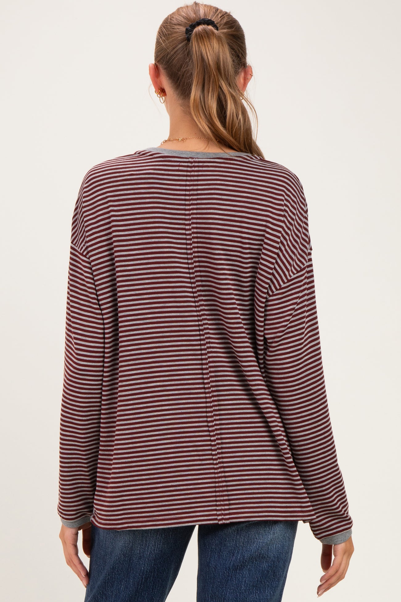 woman wearing a maroon and white striped long sleeve maternity top, showing the back view
