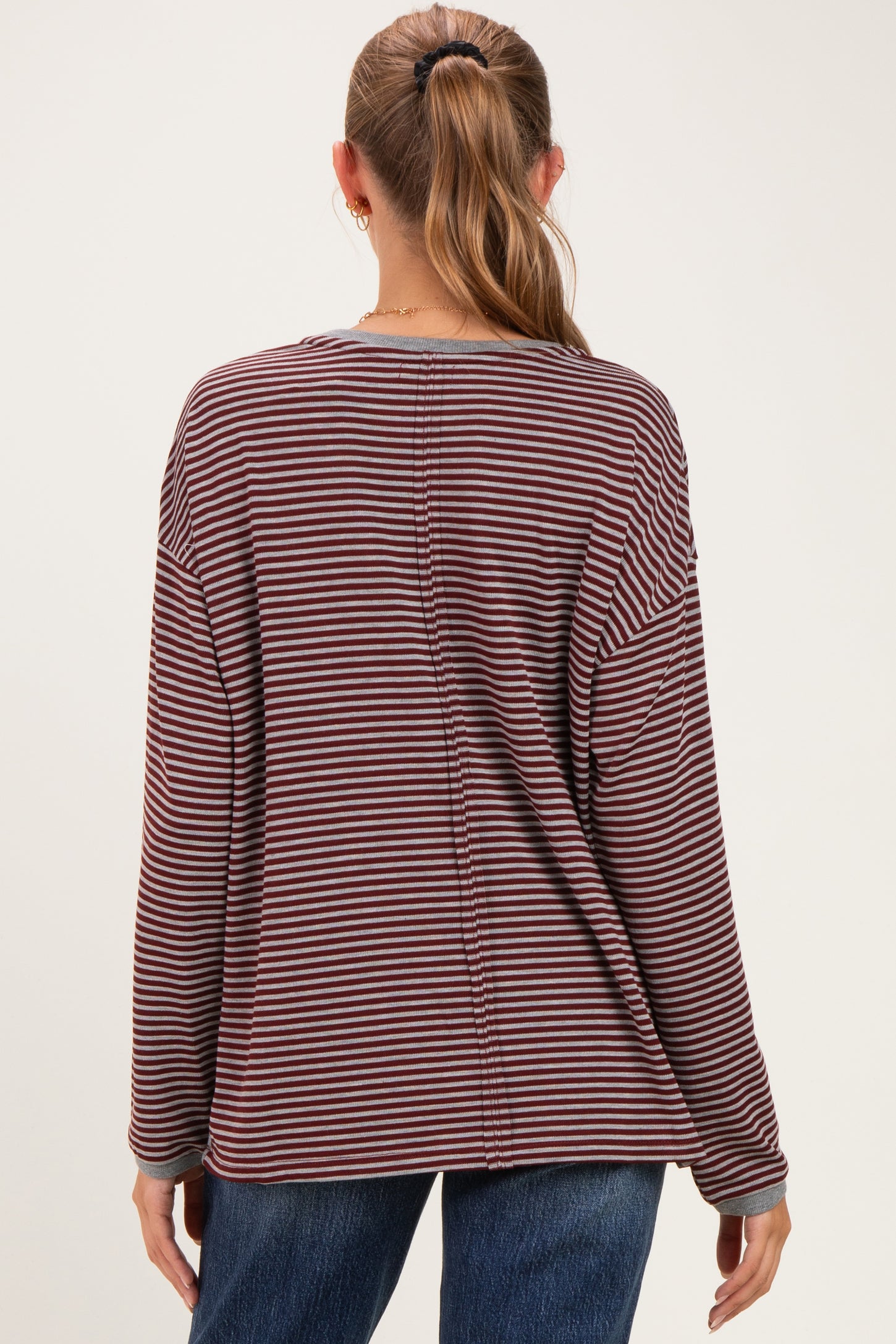 woman wearing a maroon and white striped long sleeve maternity top, showing the back view