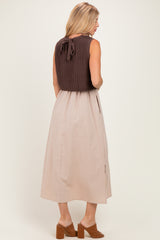 woman wearing a brown knitted top with a back tie and a beige midi skirt, standing with her back facing the camera