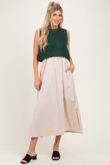 woman wearing a dark green knitted cropped sweater over a light beige maxi dress with pockets